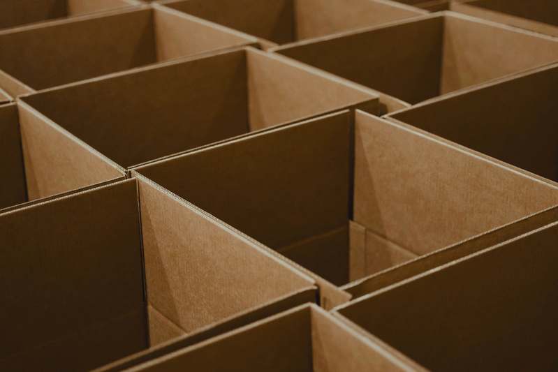 A blogger writing notes beside a stack of velvet-lined decorative boxes and fabric swatches